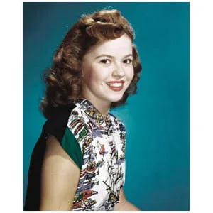 een vrouw met rood haar, gekleed in een jurk en glimlachend