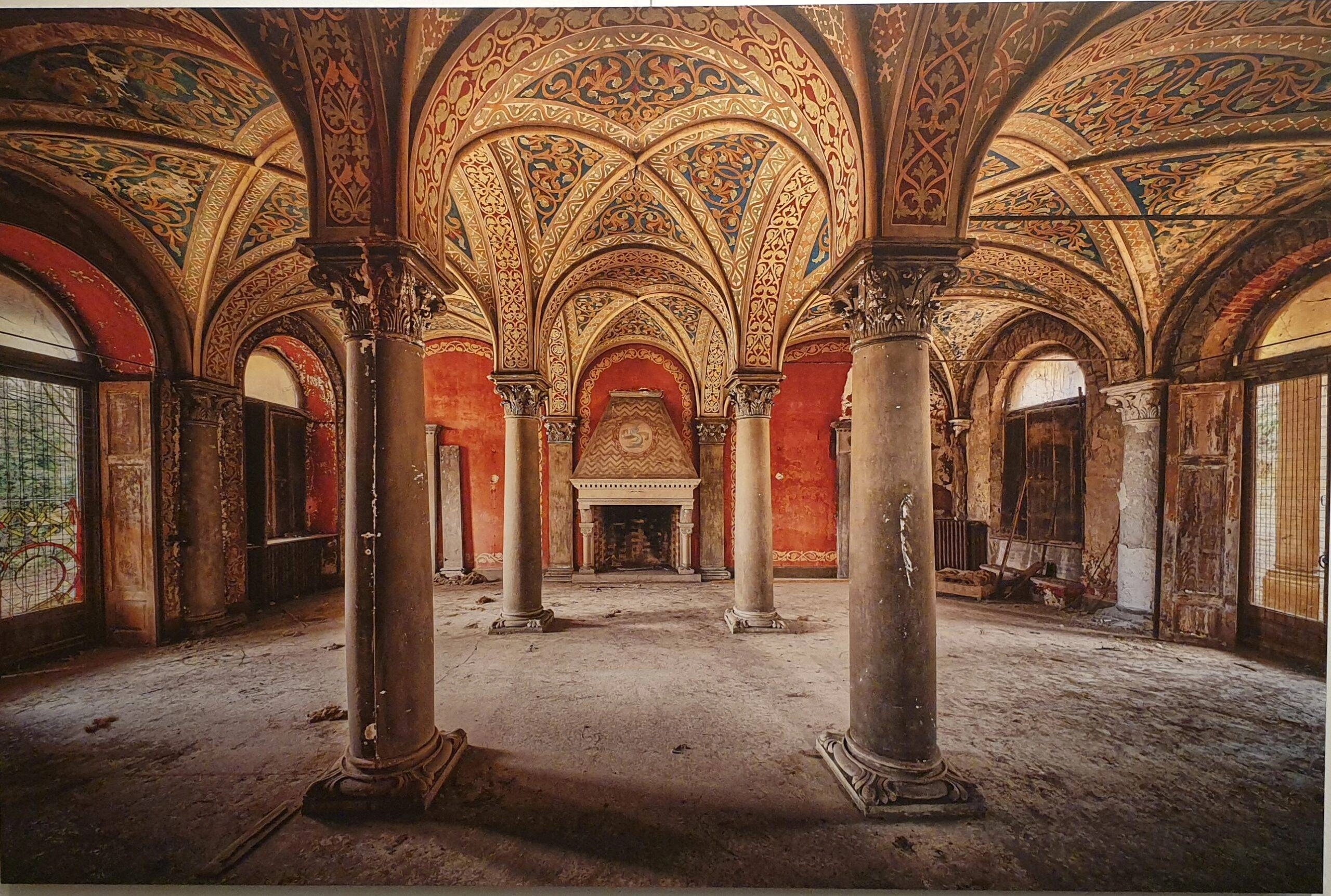 een oud gebouw met zuilen en schilderijen aan de muren