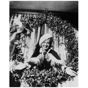 een vrouw met een kerstmuts die voor een kerstkrans staat