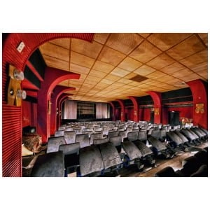 een lege zaal met rijen stoelen en rode muren