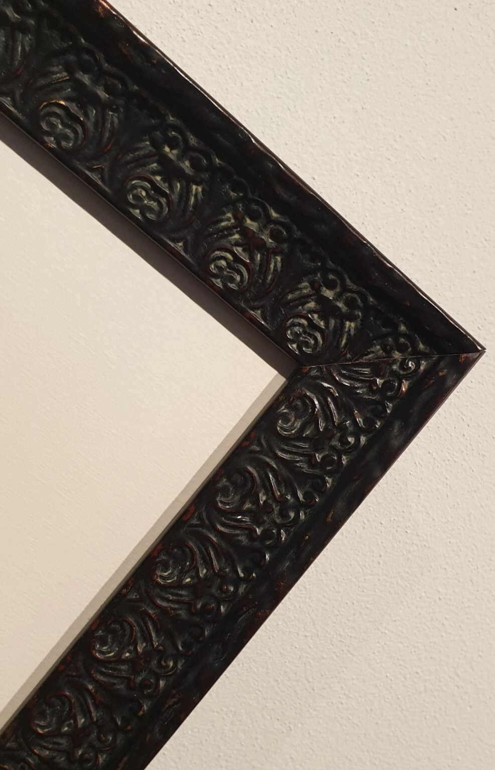 een spiegel met een zwart frame aan de muur