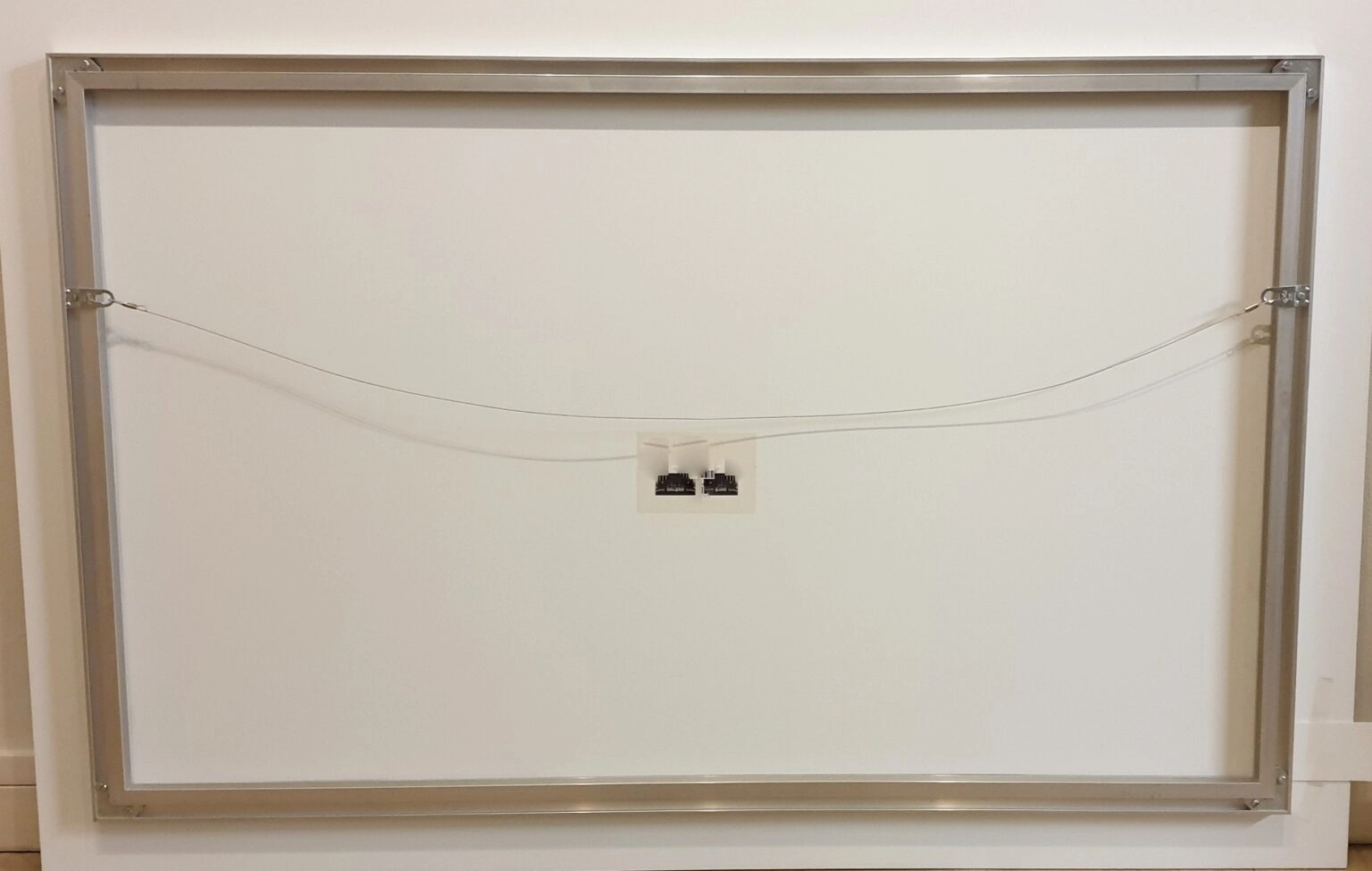 een witte muur met twee kleine elektrische draden eraan vastgemaakt